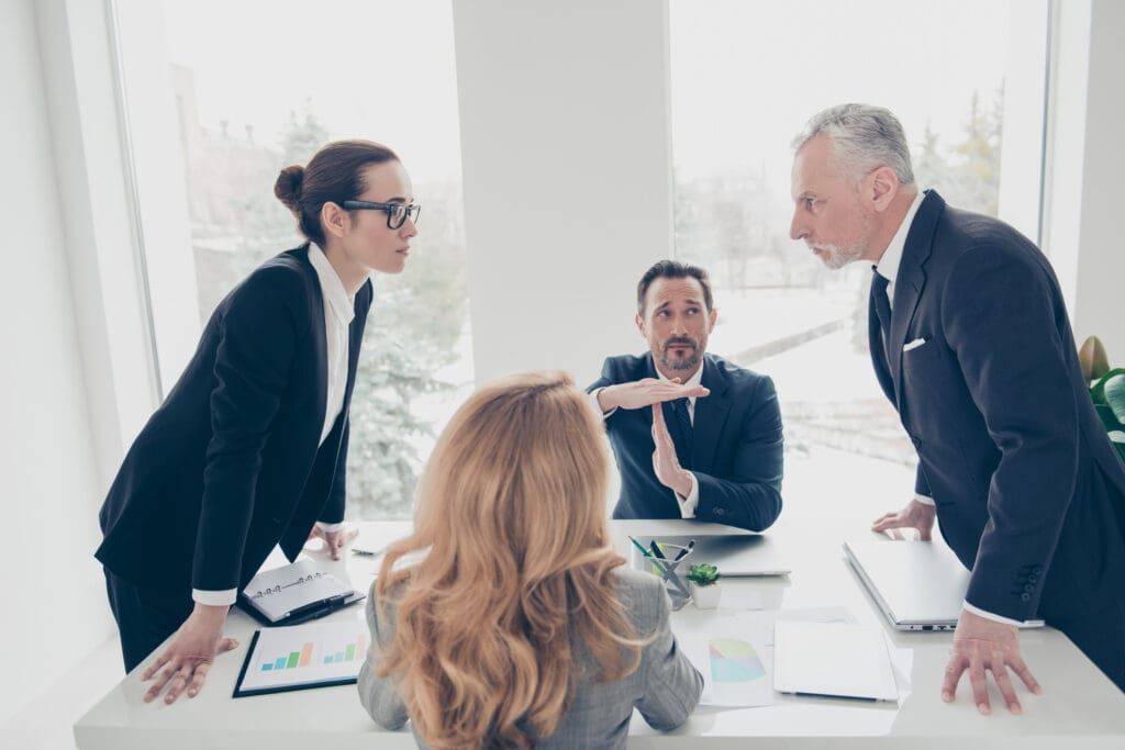 Two stylish business persons in suits having disagreement, war, conflict, standing near desktop in front of each other, face to face with disrespect expression, partner showing stop sign with hands